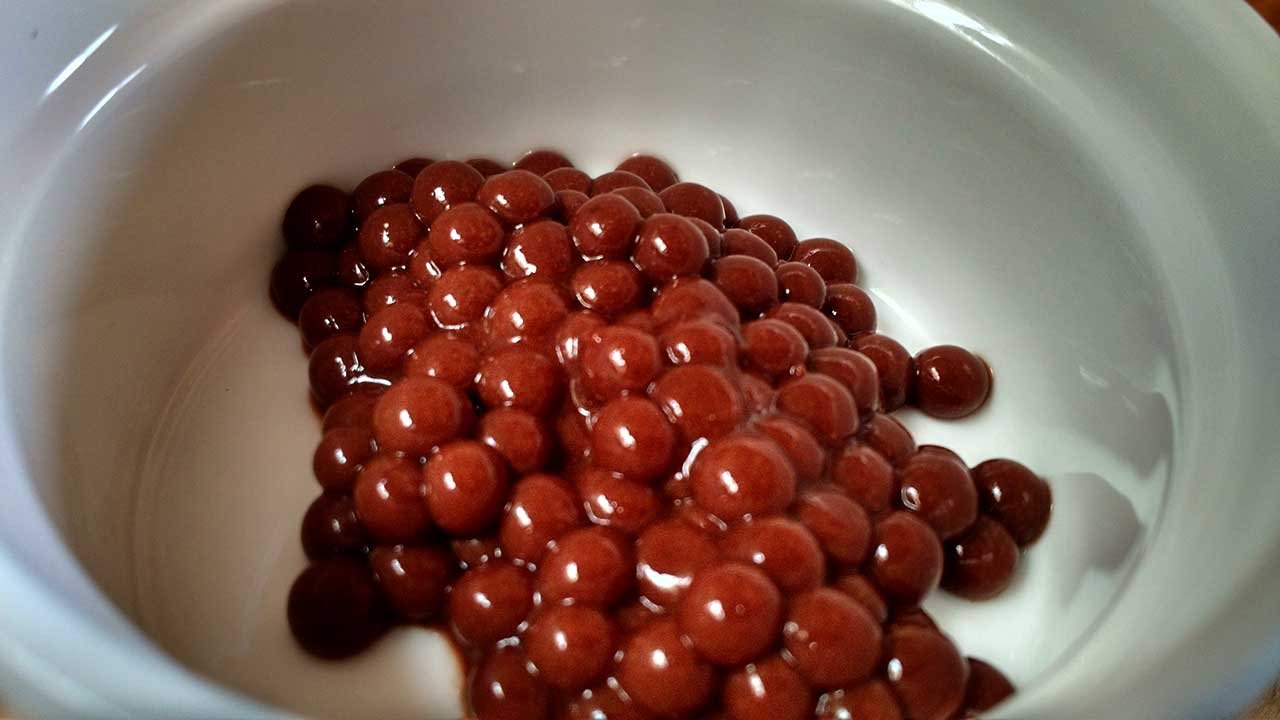 caviar de alginato de sodio, sabor cacao en recipiente blanco.